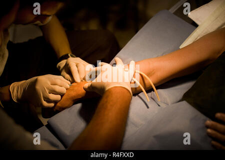 Ein Arzt spritzt eine Spritze in den Patienten am Handgelenk. Stockfoto