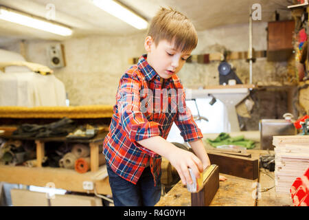 glücklich kleiner Junge mit Brett und Lineal am workshop Stockfoto