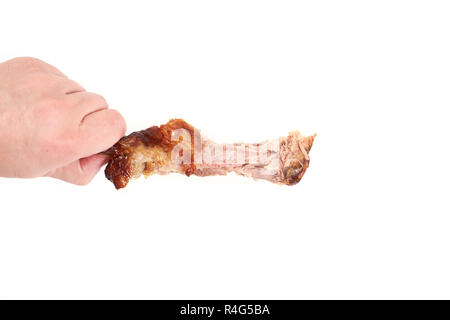 Hand mit einem Knabberte Hühnerbein, auf weißem Hintergrund Stockfoto