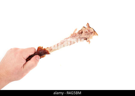 Hand mit einem Knabberte Hühnerbein, auf weißem Hintergrund Stockfoto