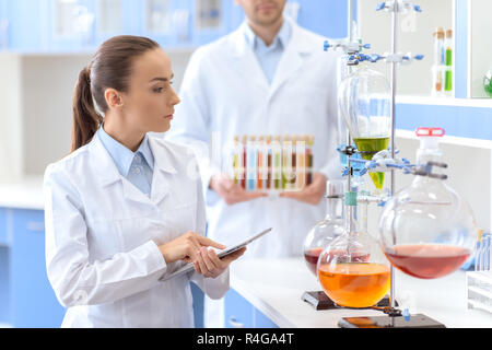 Selbstbewusste Frau Wissenschaftler digitale Tablet und Inspizieren von Reagenzien im Labor Stockfoto