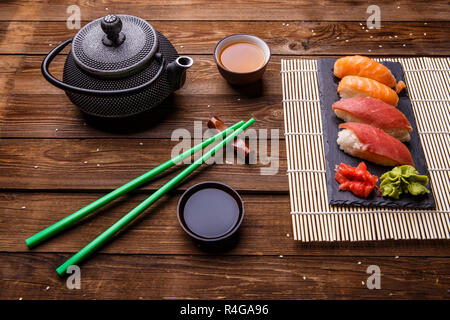 Sushi Set serviert auf grauem Stein Schiefer mit Sojasoße, grau Teekanne und Tasse Tee Stockfoto
