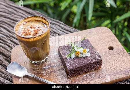 Latte Kaffee und Chocolate Brownie Kuchen auf Schneidebrett auf Holz Tabelle auf Baum Hintergrund. Latte Kaffeepause Zeit für Essen und Trinken Kategorie Stockfoto