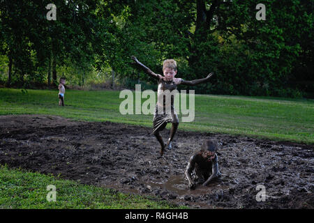 Jungen spielen im Schlamm Stockfoto