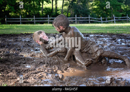 Zwei Jungen werfen Schlamm und Kämpfe in einem Schlamm kämpfen im Land Stockfoto