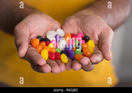 Handvoll Jelly Beans gegen gelben Hemd Stockfoto