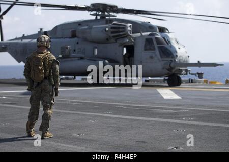 Ein Marine mit Amphibious Reconnaissance Platoon des 31 Marine Expeditionary Unit Uhren a CH-53E Super Stallion Hubschrauber für den Start vorbereiten, bevor die schnelle Seil Ausbildung an Bord der Amphibisches Schiff USS Wasp (LL 1), unterwegs in das Südchinesische Meer, Sept. 25, 2018. Fast roping ermöglicht die Marines zu schnell sonst unzugänglichen Orten von oben eingeben. Die 31. MEU, das Marine Corps' nur kontinuierlich vorwärts - bereitgestellt MEU, bietet eine flexible Kraft bereit, ein breites Spektrum an militärischen Operationen im indopazifischen Region durchzuführen. Stockfoto