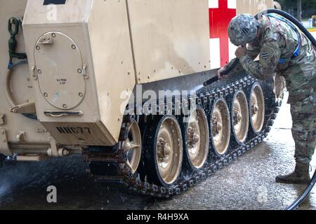 Spc. David Gerle an 2nd Battalion, 69th Armored Regiment, 2. gepanzerte Brigade Combat Team, reinigt den Track auf seine zugewiesene M113 Schützenpanzer in Fort Stewart, Ga., Okt. 3, 2018. Soldaten, saubere Fahrzeuge als Teil der regelmäßigen Wartung und Pflege der Ausrüstung. Stockfoto