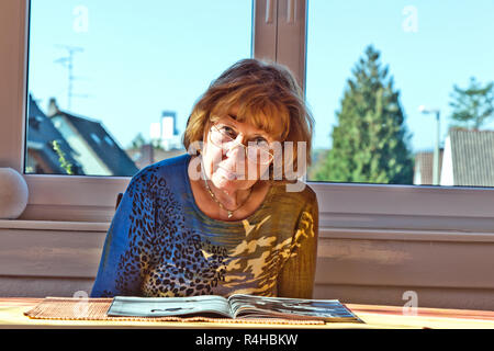 Ältere Menschen attraktive Frau zu Hause in einer Zeitschrift Stockfoto