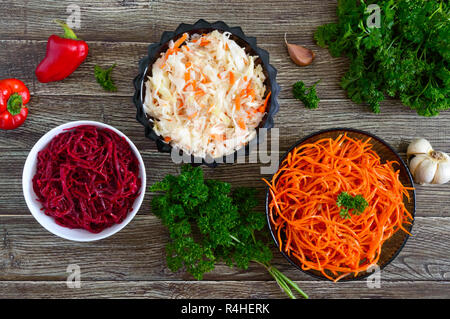 Salate aus frischem Gemüse: Kohl, Karotten, Rüben. Koreanische würzige Salate in Schalen auf einem Holztisch. Ansicht von oben. Vitamin Menü. Vegane Küche. Stockfoto