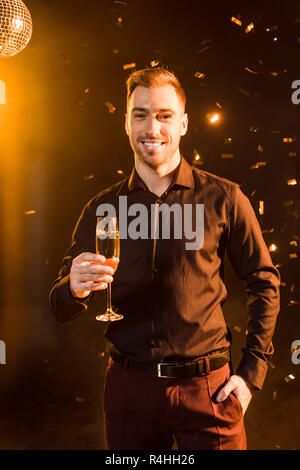 Gutaussehenden jungen Mann mit einem Glas Sekt unter Gelb auf Schwarz Stockfoto