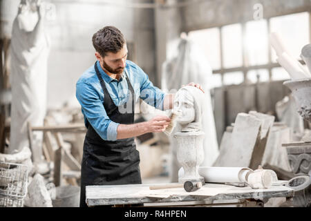 Stattliche Bildhauer bürsten Skulptur der Kopf der Frau am Arbeitsplatz in der Alten atmosphärischen Studio Stockfoto