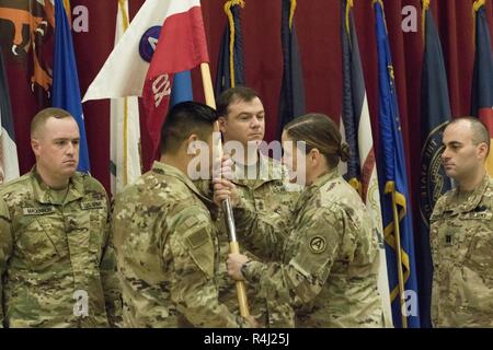 Us-Armee Oberstleutnant Lindsay R. Matthews, U.S. Army Hauptsitz und Sitz Bataillonskommandeur, übergibt das Unternehmen guidon zu US-Armee Kapitän Bryant C. Ahn, eingehende USARCENT Hauptsitz und Sitz der Firma Commander, Fortsetzung der Tradition bei einem Befehl Zeremonie im Camp Arifjan, Kuwait, 27. Oktober 2018. Mit der Übertragung, das Erbe der Einheit ist als Baustein für die zukünftige Wertentwicklung und die Erreichung weitergegeben. Stockfoto