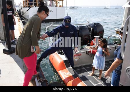 Feuerwehrmann Falcon Piner, Coast Guard Station San Diego, hilft die Gäste an Bord eines 33-Fuß-Special Purpose Handwerk - Strafverfolgung, während einer Open House bei Coast Guard Sektor San Diego Okt. 28, 2018. Die Open House war in Verbindung mit Fleet Week San Diego statt und wurde der Gemeinschaft die Möglichkeit, sich mit ihren lokalen Küstenwache zu interagieren. Stockfoto
