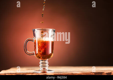 Braune Spritzer, Trinken aus der Tasse Tee auf einem braunen Hintergrund Stockfoto