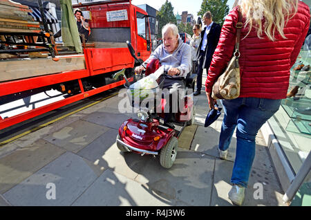 Mann, der ein Mobility Scooter auf dem Bürgersteig in Central London, England, UK. Stockfoto