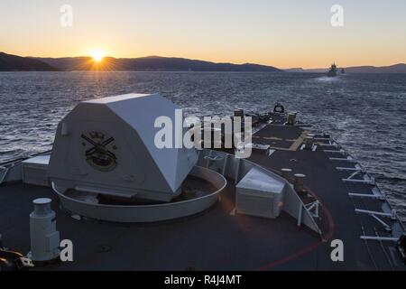 Her Majesty's Canadian Ship (Hmcs) VILLE DE QUÉBEC folgt NATO-Kriegsschiffe in Trondheim Fjord bei Sonnenaufgang während der Übung TRIDENT ZEITPUNKT am 29. Oktober 2018. Stockfoto