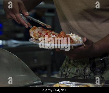 Norwegische See (Nov. 1, 2018) der Luftfahrt Bootsmann Mate (Handling) Airman Eddy Bryant serviert Speisen in der Küche an Bord der Wasp-Klasse amphibisches Schiff USS Iwo Jima (LHD 7) Nov. 1, 2018. Iwo Jima ist derzeit die Teilnahme an Trident Zeitpunkt 2018, das eine NATO-geführte Übung zur NATO Response Forces zu zertifizieren und Interoperabilität zwischen den teilnehmenden NATO-Verbündete und Partner Nationen. Stockfoto