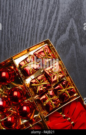 Weihnachten Spielzeug auf schwarzem Holz- Hintergrund. Rot, Gold Weihnachten Dekoration, Bälle Bögen Geschenke Ansicht von oben flach Xmas2019 Stockfoto