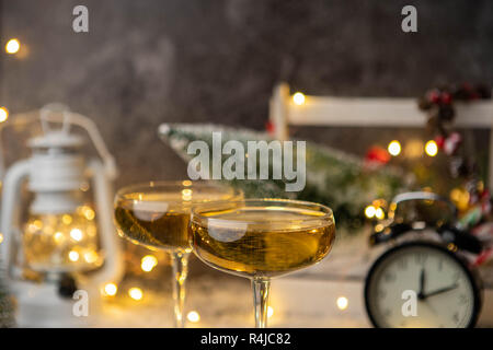 Foto von zwei Weingläser auf unscharfen Hintergrund mit Weihnachtsbaum, Laternen, Uhr Stockfoto