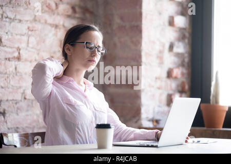 Müde Geschäftsfrau massieren angespannte Muskeln des Halses am Arbeitsplatz Stockfoto