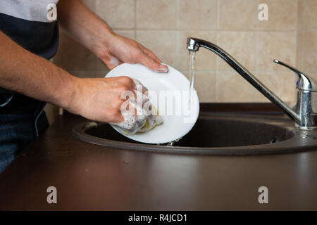 Foto von Seite der Hände des Menschen waschen Transparente Becher in Waschbecken Stockfoto