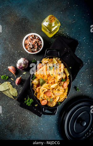 Deutsch, Polnisch, Österreichische Küche Teller, Bigos - Sauerkraut cabbage geschmort mit Fleisch, Pilzen und Wurst, in kleinen Pan auf dunklen konkreten Hintergrund. T Stockfoto