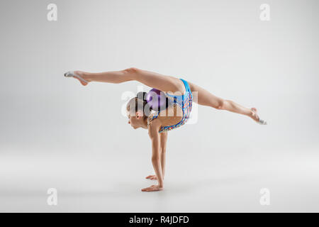 Die jugendlich weiblich Mädchen Gymnastik Übungen isoliert auf einem grauen studio Hintergrund. Die Gymnastik, Dehnen, Fitness, Lifestyle, Ausbildung, Sport Konzept Stockfoto