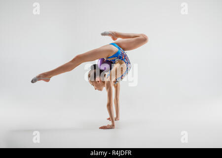 Die jugendlich weiblich Mädchen Gymnastik Übungen isoliert auf einem grauen studio Hintergrund. Die Gymnastik, Dehnen, Fitness, Lifestyle, Ausbildung, Sport Konzept Stockfoto