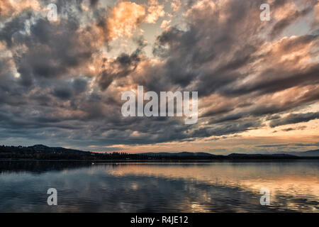 Dunkle Wolken bei Sonnenuntergang über dem See von Varese in einer ruhigen Herbst Landschaft mit Hügeln am Horizont Stockfoto