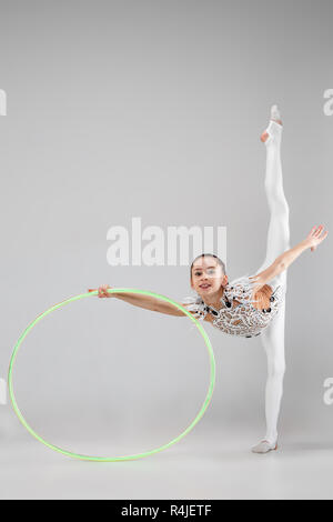 Die jugendlich weiblich Mädchen Gymnastik Übungen mit Reifen auf einem grauen studio Hintergrund isoliert. Die Gymnastik, Dehnen, Fitness, Lifestyle, Ausbildung, Sport Konzept Stockfoto