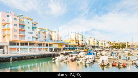 Sportboote am Jachthafen von Albufeira mit pastellfarbenen postmodernen Ferienwohnung Bausteine im Hintergrund Stockfoto