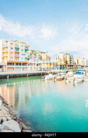 Sportboote am Jachthafen von Albufeira mit pastellfarbenen postmodernen Ferienwohnung Bausteine im Hintergrund Stockfoto