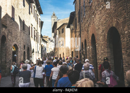 Masse der Touristen Menschen gehen zusammen gezogen und mit der Straße voll in San Gimignano in der Provinz Siena in der Toskana, Italien. Urlaub und Kultur in einem med. Stockfoto