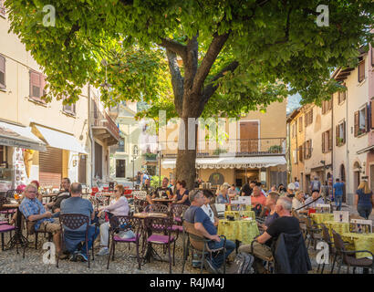 Street Café im Zentrum des mittelalterlichen Dorfes von Malcesine. Es ist einer der charakteristischsten Orte des Gardasees in der Provinz von Verona, Italien. Stockfoto