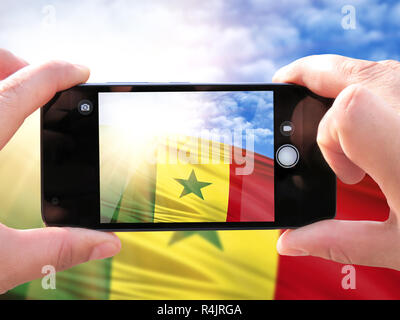 Das Konzept des Tourismus und Reisen. Die Hände der Männer bilden ein Telefon Foto der Flagge von Senegal. Auf dem Smartphone Nahaufnahme der Fahne. Phot Stockfoto