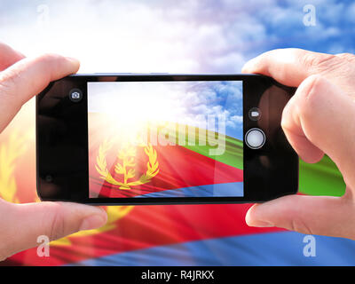 Das Konzept des Tourismus und Reisen. Die Hände der Männer bilden ein Telefon Foto der Flagge von Eritrea. Auf dem Smartphone Nahaufnahme der Fahne. Phot Stockfoto