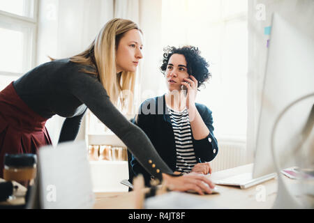 Zwei weibliche Geschäftsleute mit Smartphone in einem modernen Büro. Stockfoto
