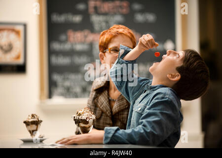 Lächelnde Mutter und Sohn genießen Eis Eisbecher. Stockfoto