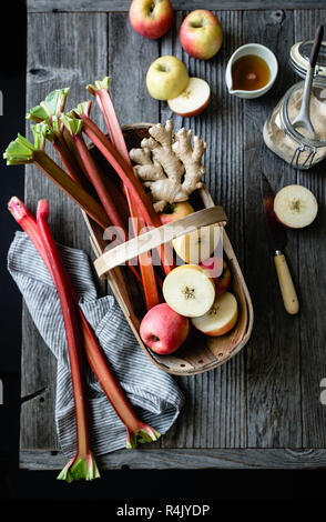 Äpfel und Rhabarber in einem Korb auf einem hölzernen Hintergrund Stockfoto