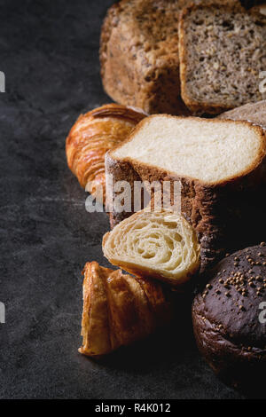 Vielzahl von frisch gebackenen Roggen, Dinkel, Weizen craft Artisan Brot, ganz und geschnitten, auf schwarzem Hintergrund Textur. Nahaufnahme Stockfoto