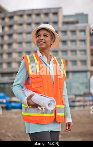 Stolz junge Ingenieurin Holding eine Rolle der Baupläne auf einer Baustelle. Stockfoto