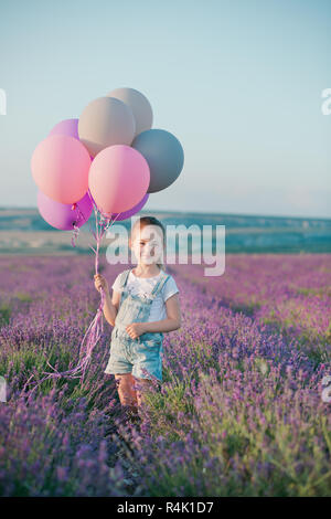 Ein Mädchen in einem Lavendelfeld mit Ballons Stockfoto