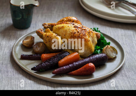 Ganze braten Poussin mit violetten und roten Möhren, Grünkohl, geschmorte Schalotten und Soße Stockfoto