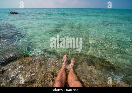 Ein Tourist testet das Wasser auf Mosambiks Paradise Island. Stockfoto