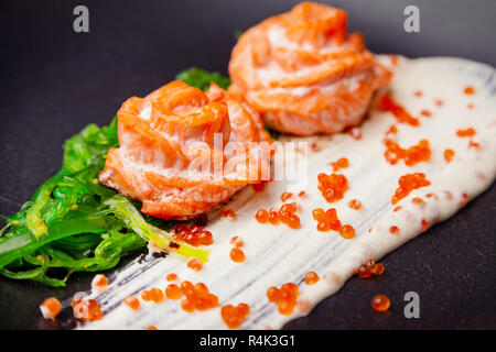 Gekochten gebackenen Lachs in Sahnesoße garniert mit hiyashi Algen und roter Kaviar Stockfoto