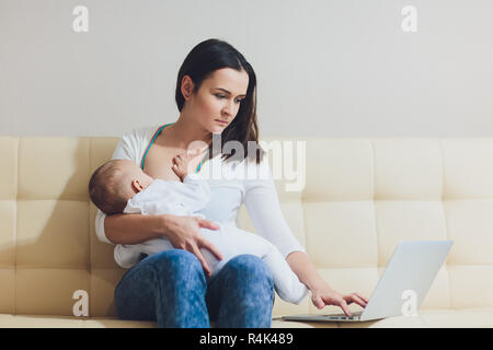 Schöne junge Mutter arbeiten mit Laptop und Ihr neugeborenes Baby beim Stillen zu Hause. Mom-business Frau. Stockfoto