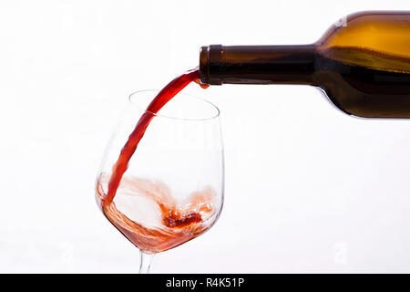 Rotwein gegossen aus einer Flasche in ein Glas Wein Stockfoto