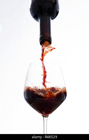 Rotwein gegossen aus einer Flasche in ein Glas Wein Stockfoto