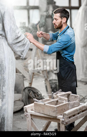 Stattliche rauchen Bildhauer schlagende Stein Skulptur mit Hammer und Meißel im Studio Stockfoto